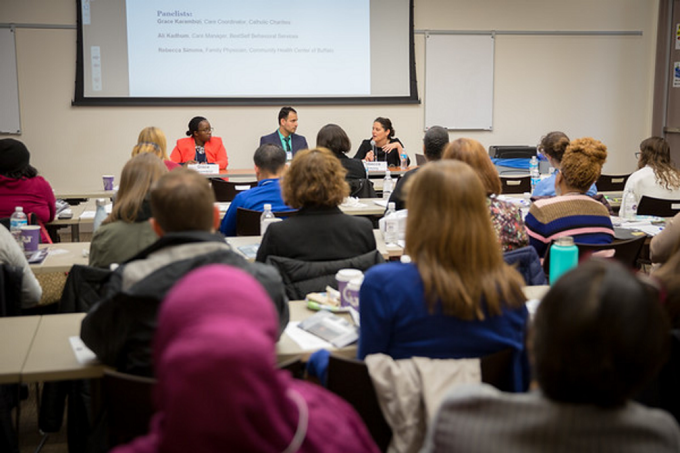 People sitting and presenting to a room full of people. 