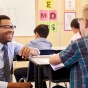 Teacher smiling beside student's desk. 