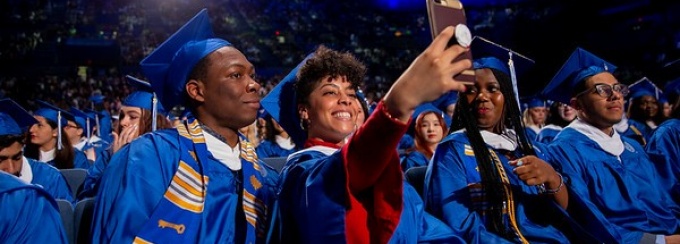 Picture of Graduating seniors sitting in a row together taking a selfie. 