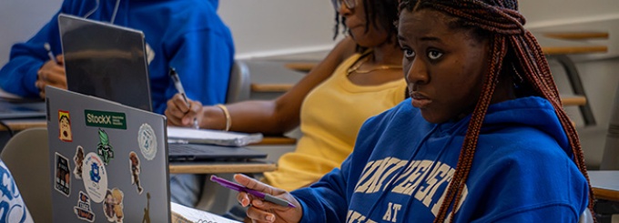 A student sits in front of her laptop, paying attention in class. 