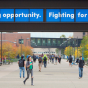 Students walk across UB&rsquo;s North Campus under a bridge banner reading, &ldquo;Creating opportunity. Fighting for justice.&rdquo;. 