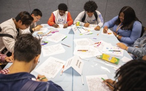 Eight students working at a round table. 