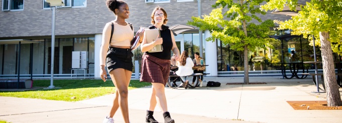 Students walking on a pathway outside Greiner Hall and the Ellicott Complex on UB’s North Campus. 