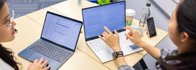Two students working side by side on laptops. 