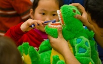 Young boy practicing dental hygiene on stuffed animal. 