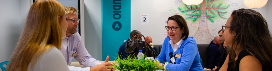 A group of people speaking around a table. 