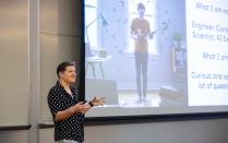 An instructor stands in front of a presentation slide on AI. 