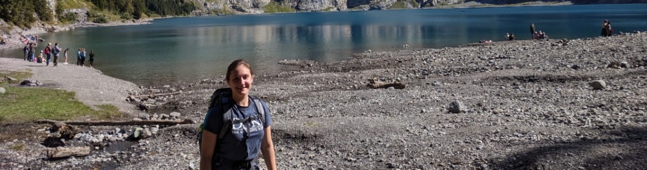 Photo of Patricia Johnson on a hike in front of a lake called Oeschinensee. 