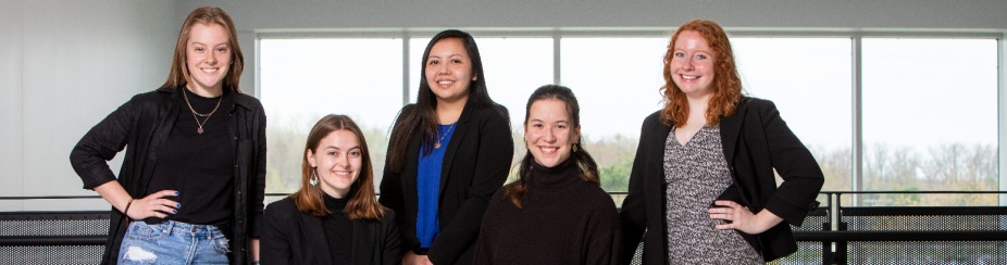 Five students standing in the One World atrium. 