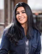 Photo shows a person with dark hair smiling at the camera. 