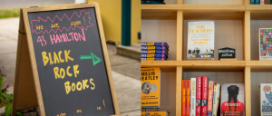 Photo shows a sign with "43 Hamilton Black Rock Books" pointing to a shop with books on a shelf. 