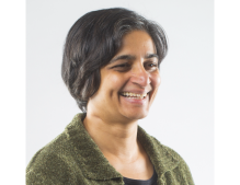 Woman with short hair, wearing a green sweater. 