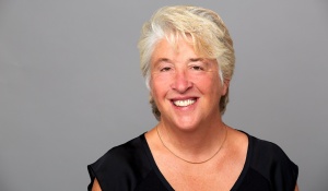 A woman with white hair, smiling at the camera. 