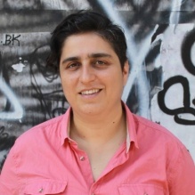 Image of a woman with short brown hair wearing a pink button up shirt. 