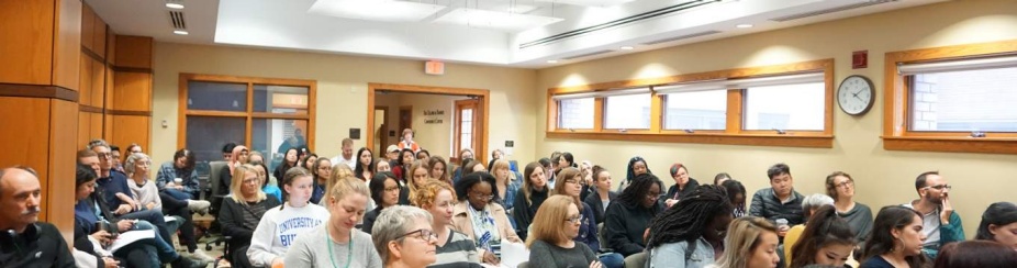 Photo of large group of different people sitting in for a lecture. 