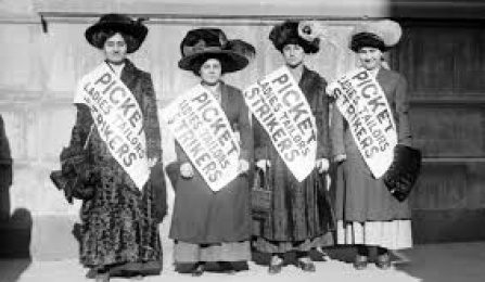 This is a photo of the Uprising of 20,000 (1909). It shows four women wearing black hats and all wearing a sash that reads - "Picket Ladies Tailors Strikers". 