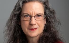 Woman with dark hair, smiling at the camera. 