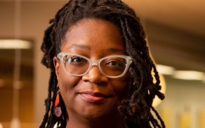Woman wearing glasses, smiling at the camera. 