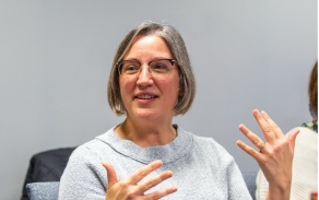 Woman with short hair talking animatedly with her hands. 