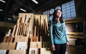 Woman standing in front of pieces of wood. 