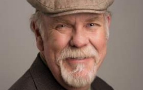 Main in hat, wearing a suit and tie, smiling at the camera. 