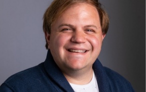 Person smiling at the camera wearing a blue cardigan. 