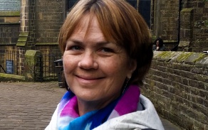 Woman with short hair and a colorful scarf smiling at the camera. 
