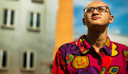 Person wearing glasses and a bright floral shirt, outdoors. 