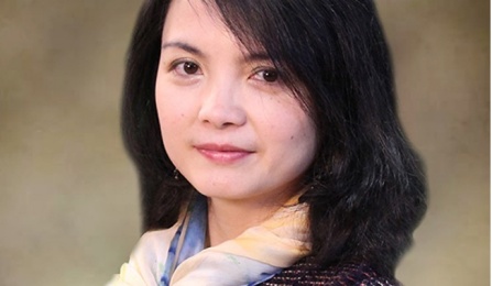 Photo shows a woman with dark hair, wearing a scarf and looking at the camera. 