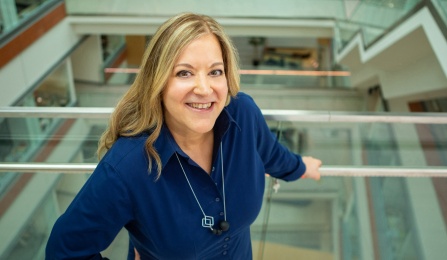 A woman with brown hair, wearing a blue shirt, smiling at the camera. 