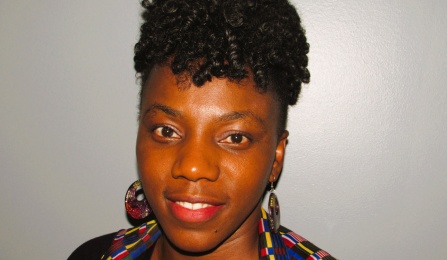 A woman with dark curled hair, smiling at the camera. 