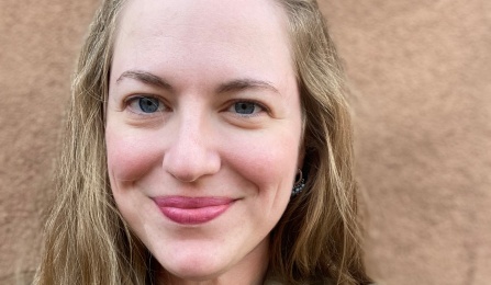 A woman with dark blonde hair, wearing a green shirt, smiling at the camera. 