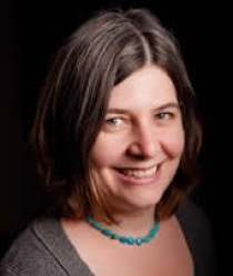 Woman with brown hair, smiling at the camera. 