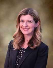 Woman with blond hair wearing a black blazer, smiling at the camera. 