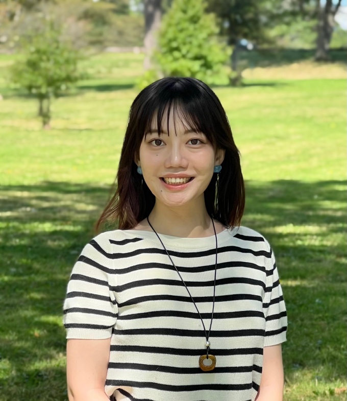 A smiling woman with dark hair outdoors. 