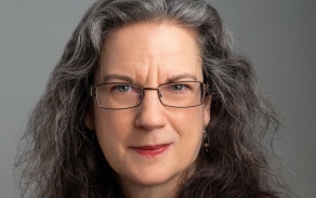 Zoom image: Woman in red blazer, smiling at the camera. 