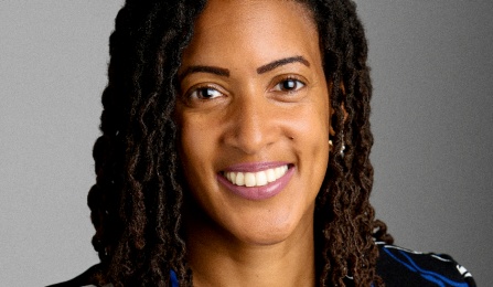 Woman with long hair wearing a colorful blazer. 