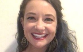 Photo shows a woman with dark hair smiling at the camera. 