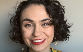 Photo shows a woman with dark hair and a floral shirt smiling at the camera. 