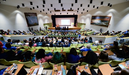 students learning from scientists in auditorium. 