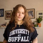 Image of Reese Betts, who has long, wavy brown hair, wearing a black University at Buffalo T-shirt. 