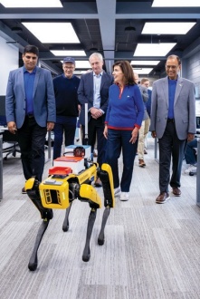 Gov. Kathy Hochul walks with a robot dog, professors and UB president Satish K. Tripathi in 2025. 