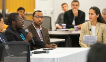 Zoom image: Steven Sanyu, Theo Herman, and Abdi Farah (from left to right) from the Buffalo refugee community speak on the topic of housing at the 6th Annual Refugee Health Summit while Dr. Samina Raja (on the right) facilitates. 