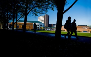 Two people walking with North Campus in the background. 