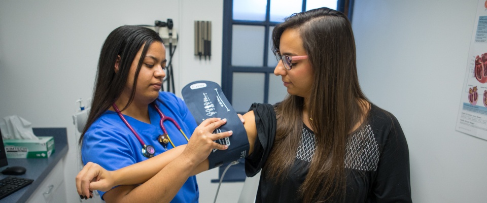 A nurse is placing a blood pressure cuff on a patient in a clinic. 