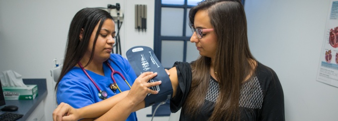 A nurse is placing a blood pressure cuff on a patient in a clinic. 
