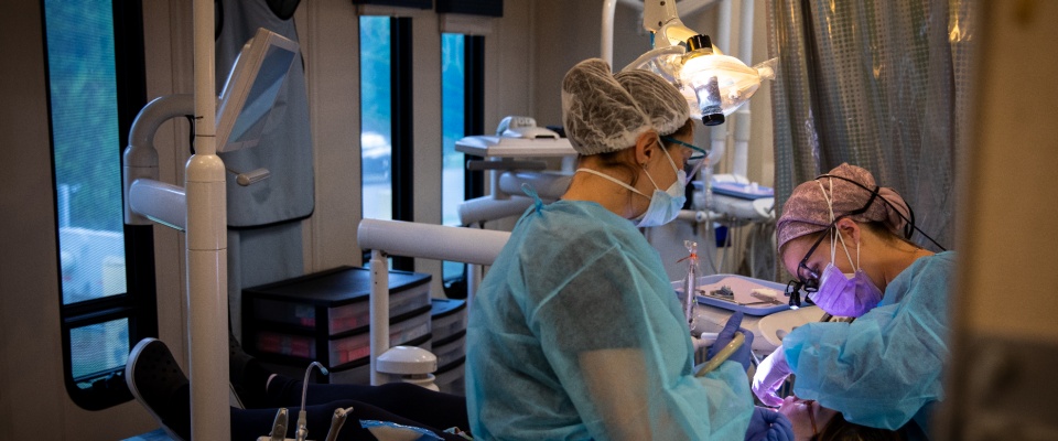 A dental assistant providing care to a patient in the van. 