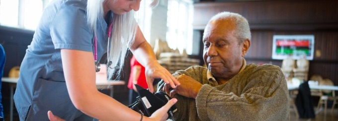Healthcare working taking blood pressure of a older patient. 