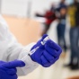 Person wearing gloves preparing a vaccine syringe. 