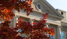 Photo of Crosby Hall with rust and gold colored fall leaves in the foreground. 